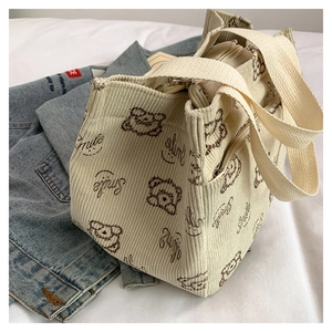 Detailed close-up of corduroy tote bag texture with cute bear print and zipper closure