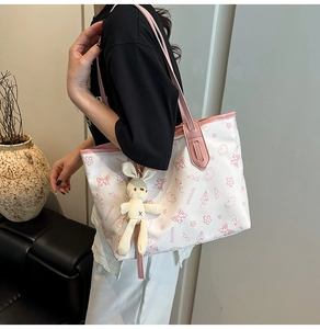 Detail of white tote bag with pink trim, cartoon patterns and rabbit plush pendant