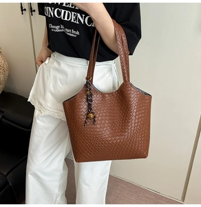 Close-up of brown woven texture tote bag with stylish knot charm on shoulder