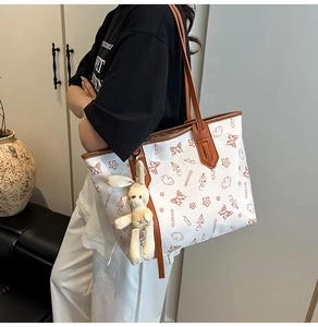 Close-up of white tote bag with butterfly prints and a cute plush rabbit pendant charm