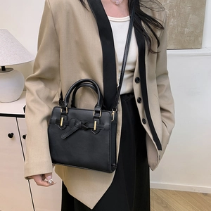 Sac à bandoulière minimaliste en cuir noir avec nœud décoratif et détails dorés chic