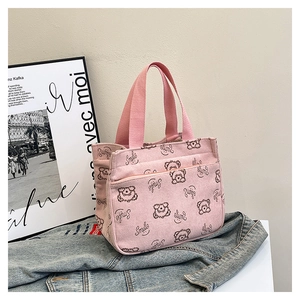 Detail view of pink corduroy tote bag with cartoon bear prints on a denim jacket background