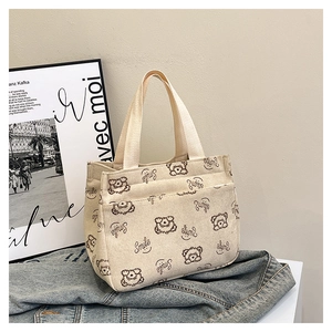 Detail of cartoon bear print and pocket on beige corduroy tote handbag for daily use
