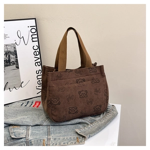 Detailed texture of brown corduroy tote bag featuring black cartoon bear and smile print