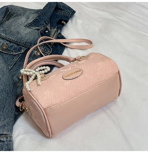 Close-up of pink snakeskin pattern bag with pearl bow charm and gold logo plate
