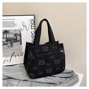 Detail of black corduroy tote bag featuring white bear prints and silver metal zipper pocket