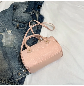 Detail of pink snake-embossed leather texture and gold hardware on a chic handbag