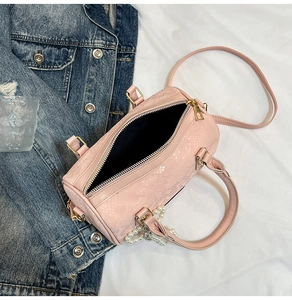 Close-up of pink snakeskin embossed Boston bag with pearl charm and gold hardware detail