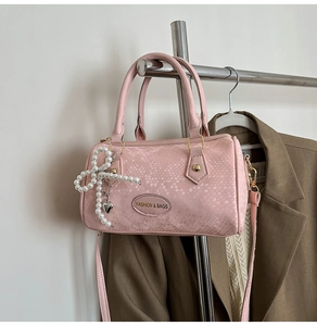 Détail du sac rose à motif serpent avec nœud perlé et plaque logo en métal