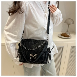 Y2K style black pleated crossbody bag with silver butterfly buckle and chain on model