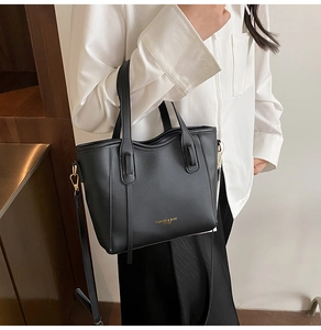 Detail view of black leather tote bag featuring gold lettering and adjustable shoulder strap