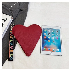 Detail view of red heart leather clutch with LOVE wristlet next to an iPad mini for scale