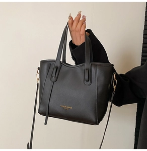 Close-up of black leather tote bag with gold logo text and dual handles detail