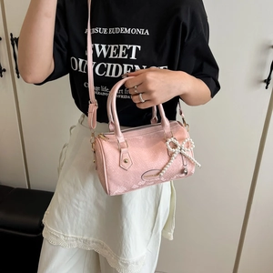 Sac cylindre rose avec texture serpent et breloque nœud en perles blanches