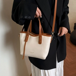 Minimalist cream and brown leather bucket bag shown with a stylish casual outfit