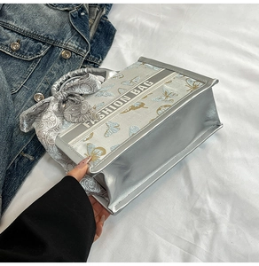 Detail of silver metallic tote bag with blue butterfly print and decorative silk scarf
