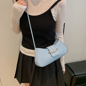 Minimalist light blue shoulder bag with golden buckle shown on a model for daily commute
