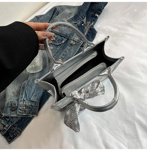 Detailed interior of silver metallic handbag featuring zipper pocket and paisley scarf