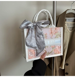 Detailed view of pink embroidered tote bag with flower pattern and decorative silk scarf
