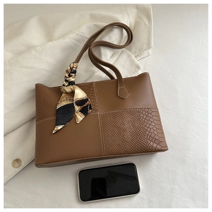 Vista superior de bolso tote marrón grande con textura de cocodrilo y pañuelo decorativo