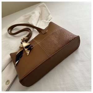 Detalle de bolso tote marrón con textura de cocodrilo y pañuelo de seda decorativo