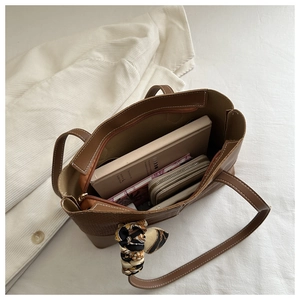 Detalle del bolso tote marrón con textura de cocodrilo, interior y pañuelo seda