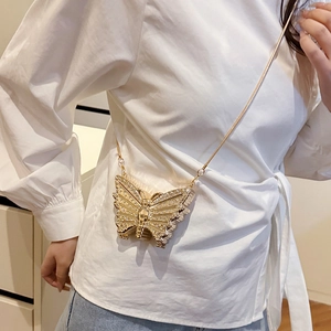 Mini sac papillon doré étincelant avec strass et chaîne sur une chemise blanche