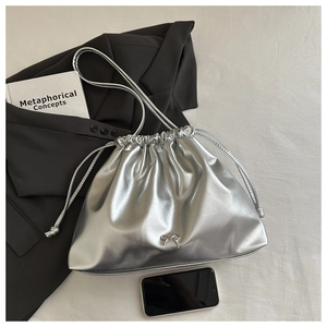 Détail du sac seau métallisé argenté avec nœud décoratif et longue bandoulière réglable