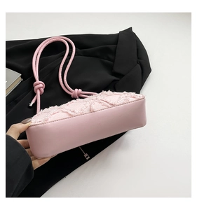 Close-up of pink quilted shoulder bag featuring fringe texture and knotted straps