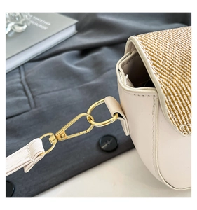 Detail of light gold ring buckle and woven texture on cream white crossbody bag