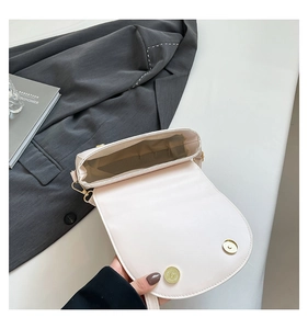 Detail showing dual magnetic gold buckles and spacious interior of the beige saddle bag