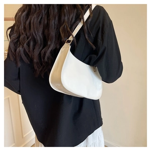Detail of white glossy underarm bag with gold buckle on a stylish model