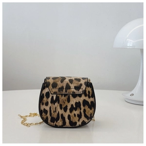 Detail of leopard print saddle bag with gold chain strap on minimalist white background
