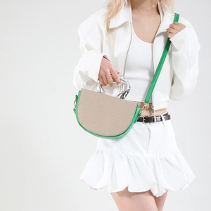 Green and beige straw saddle bag with a silver irregular metal handle and shoulder strap