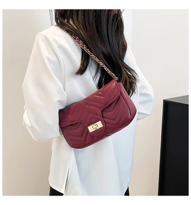 Gros plan du sac bandoulière matelassé bordeaux avec motif en V et chaîne dorée