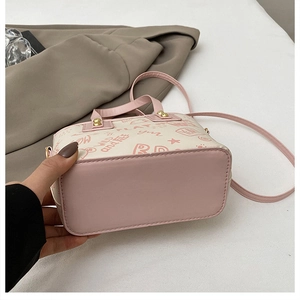 Detail view of pink and white shoulder bag featuring graffiti prints and golden hardware