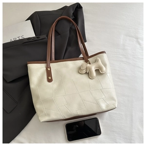 Detail of off-white leather tote bag with brown contrast handles and cute puppy charm