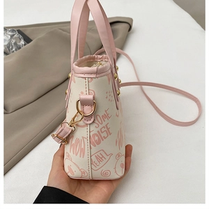Close-up of contrast tote bag with pink cartoon bear print and premium metal hardware