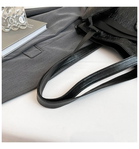 Detailed close-up of 3D skull embossed texture on a black faux leather shoulder bag