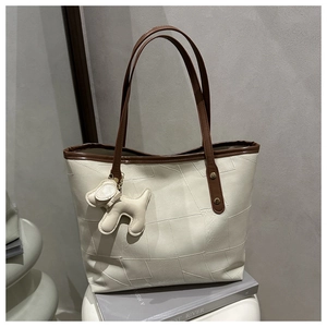 Detail of off-white tote bag with geometric stitching and cute puppy bag charm accessory