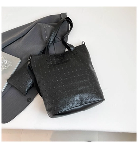 Detailed macro view of black faux leather tote set with embossed skull pattern and shoulder strap
