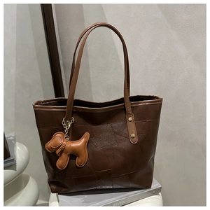 Detail of dark brown leather tote bag with geometric stitching and cute puppy pendant