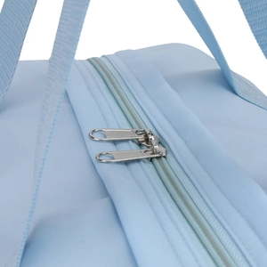 Detail of light blue travel bag featuring dual metal zippers and durable woven handles