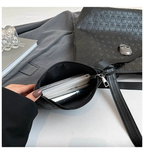 Detail of skull embossed black leather tote set with metallic skull accent and pouch