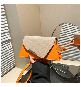 Détail d'un sac bandoulière trapèze chic en cuir orange avec rabat en tissu beige