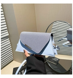 Détail du sac triangulaire bleu clair avec rabat en denim et barre métallique argentée