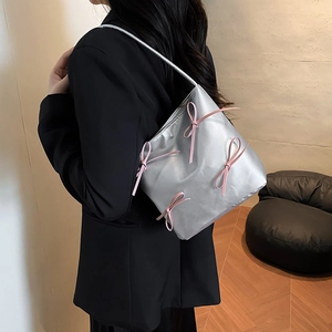 Silver metallic shoulder bag with pink ribbon bows shown on model for daily style