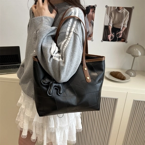 Black and brown leather tote bag with a dog charm shown on a shoulder in a room