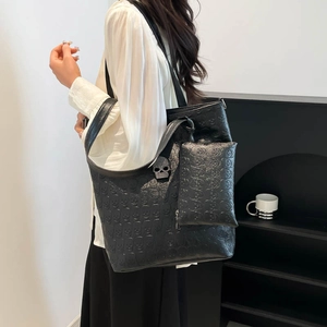 Black tote bag with embossed skull texture and matching pouch worn by a model