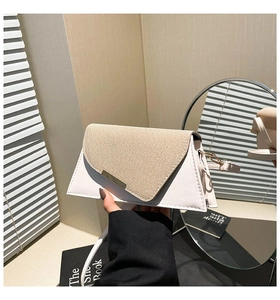 Détail du rabat tissé et du fermoir en métal doré sur le sac à main bicolore géométrique